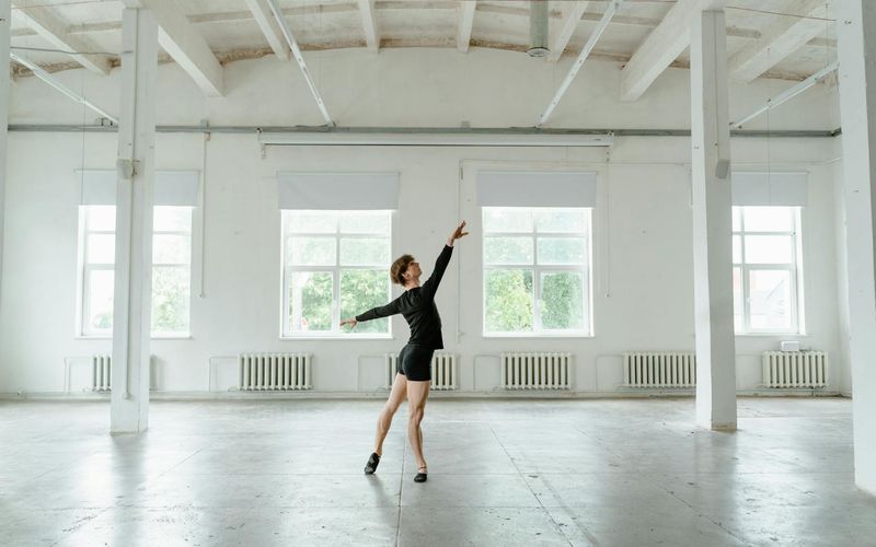 Man in a deep lunge position, focusing on form in a spacious studio.